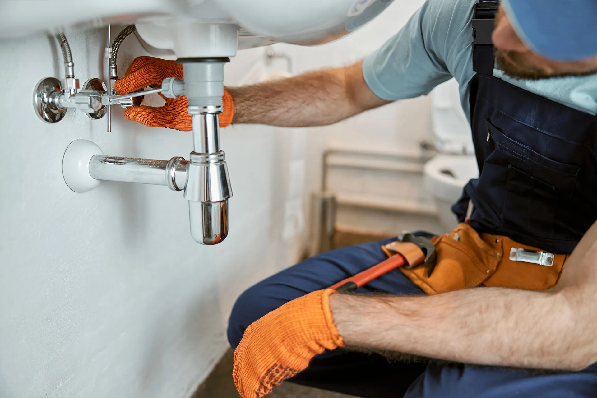 Plumber repairing pipe under sink